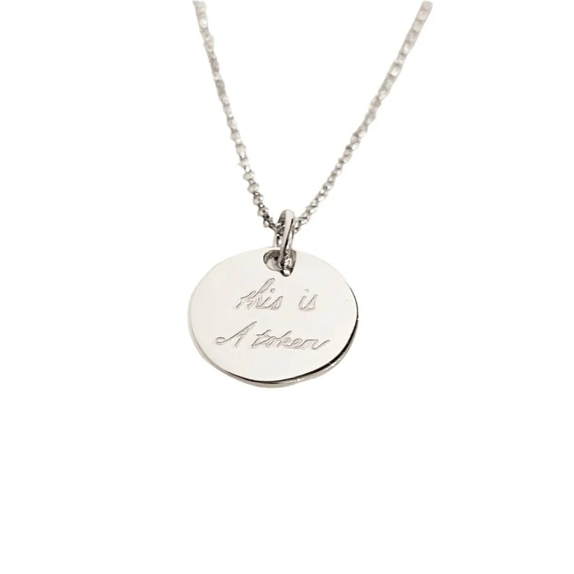 A small, round silver disc with handwritten text saying 'this is a token'