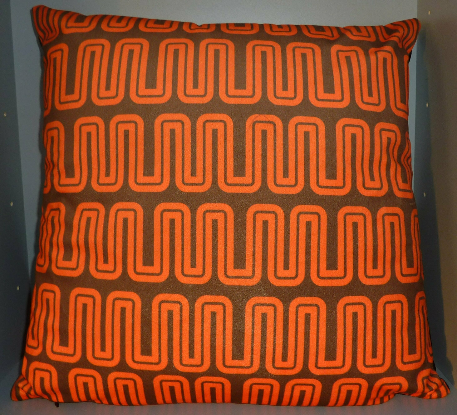Brown cushion with wavy M logos in orange