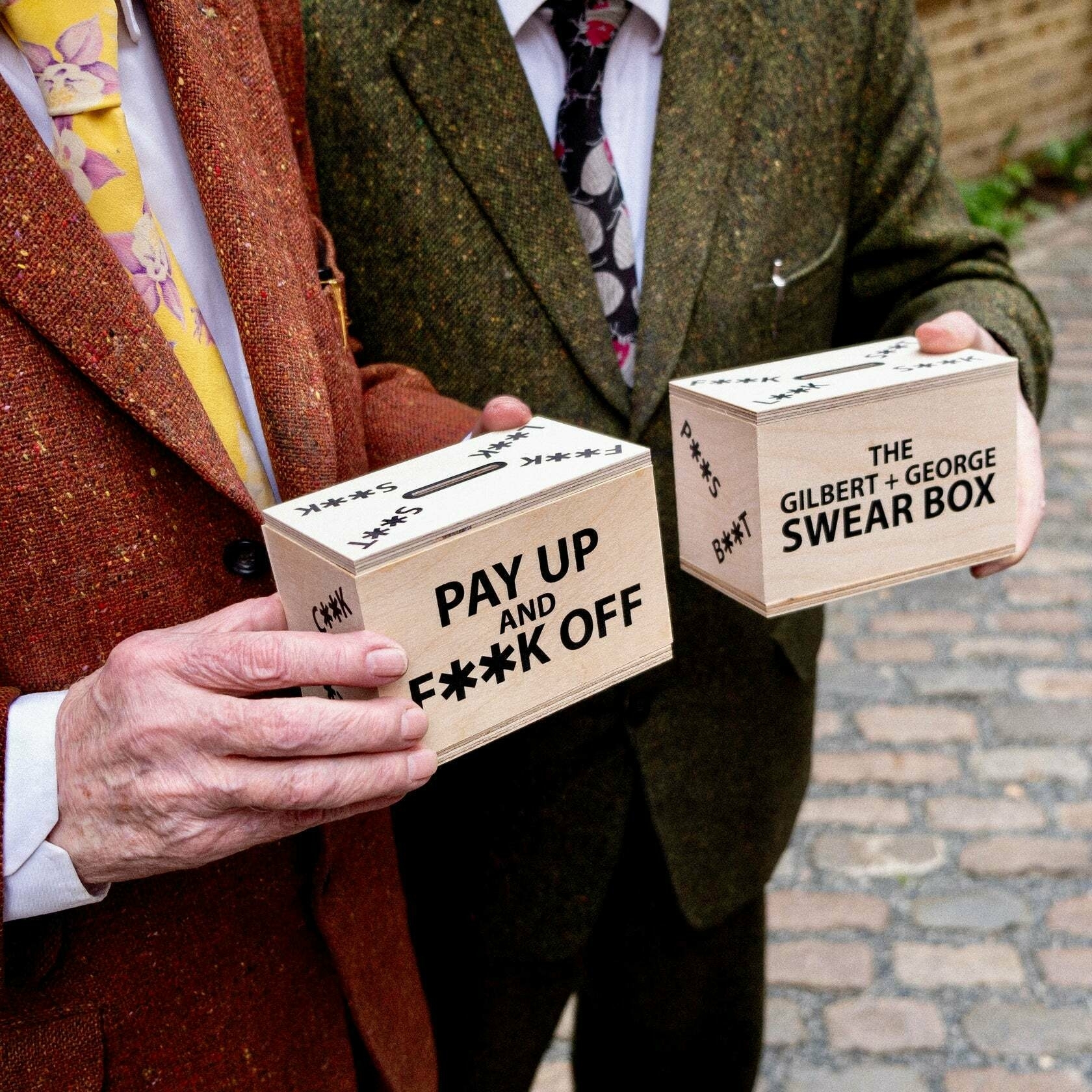 Gilbert and George holding their swear boxes